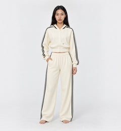 The Weekender Pants in Beige by Gallenn – model front view with wide legs and black side stripes, worn with the matching hoodie