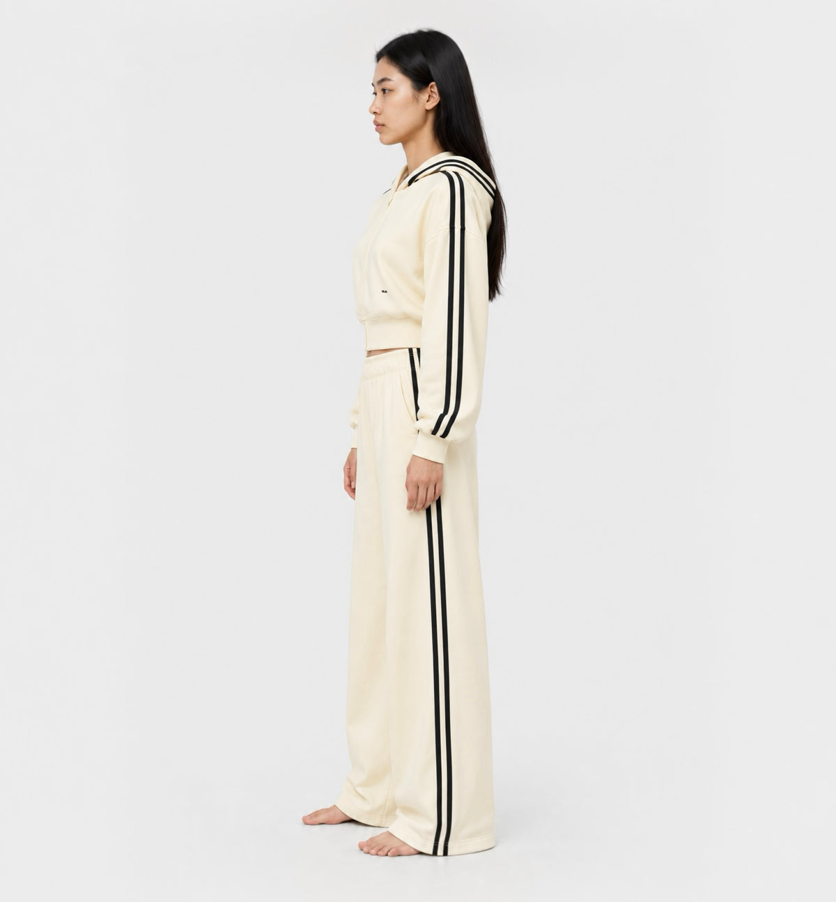 The Weekender Pants in Beige by Gallenn – model side view with wide legs and black side stripes, worn with the matching hoodie